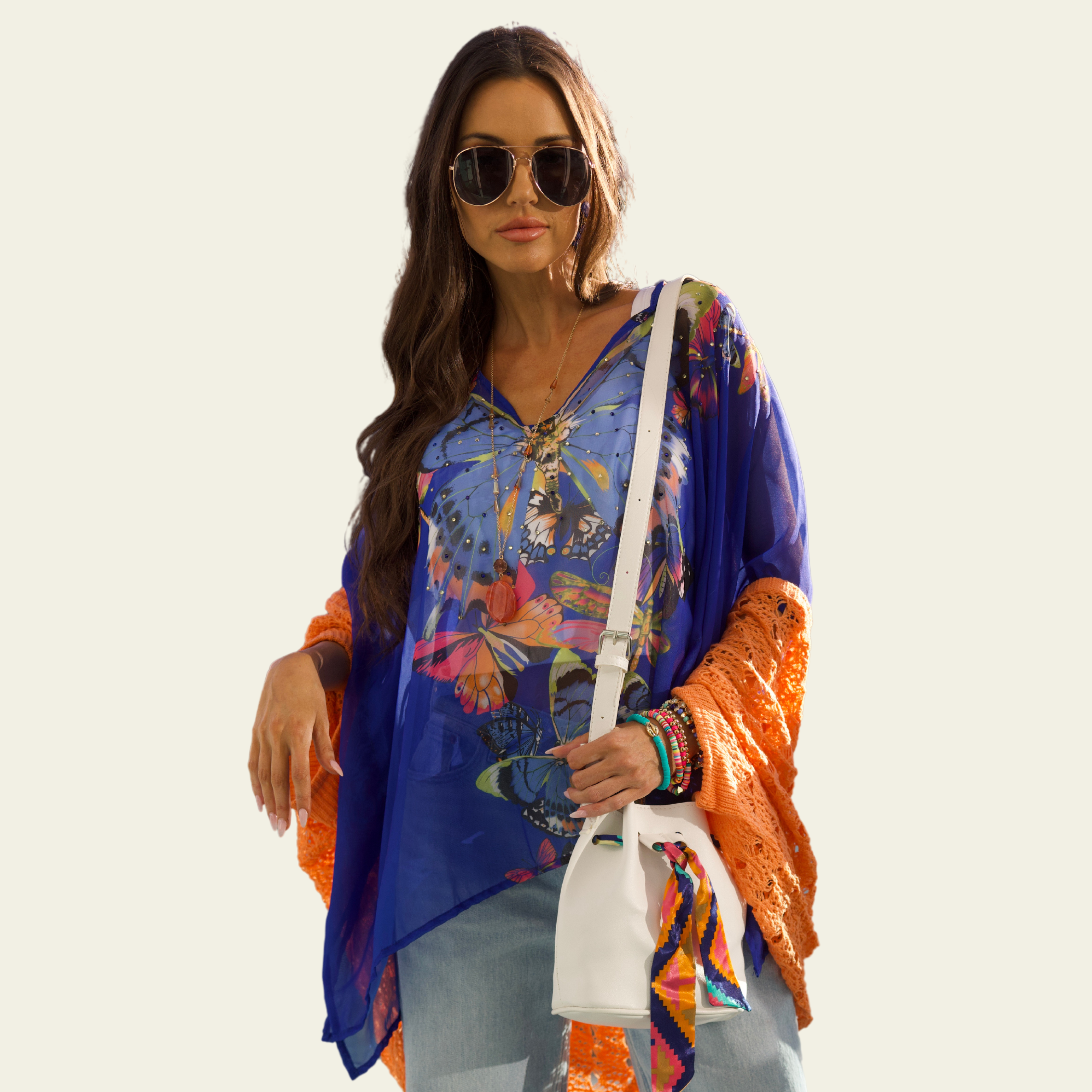 The Bijoux Terner Crystal Top Breathable Blouse is elegantly worn by the model, showcasing its lightweight fabric and graceful drape. The blouse flows effortlessly, highlighting its airy and breathable quality, perfect for warm weather. The design features a vibrant butterfly print in a mix of colorful hues, with shades of blue that complement the intricate details of the butterflies.